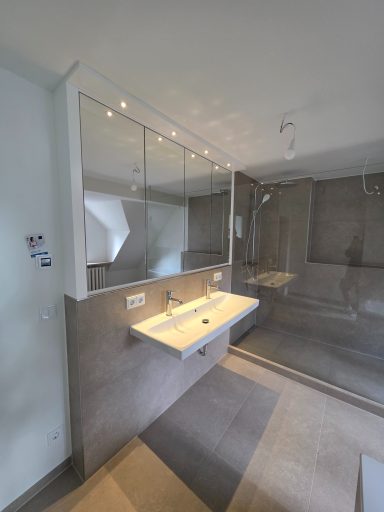 Bad-Spiegelschrank mit integrierter LED-Beleuchtung und flächenbündigen Spiegeltüren über einem Waschtisch