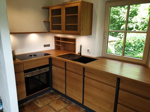 Maßgefertigte Schreiner-Küche aus Massivholz Eiche mit vertikalen schwarzen Dekorleisten und dunkler Spüle