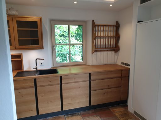 Maßgefertigte Schreiner-Küche aus Massivholz Eiche mit vertikalen schwarzen Dekorleisten und dunkler Spüle