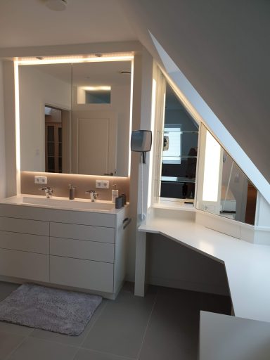 Maßgefertigter Bad-Einbauschrank in einer Dachschräge mit passgenauem Waschtisch und beleuchtetem Spiegel.